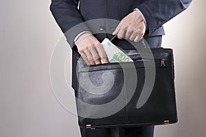 Businessman with a briefcase full of money in the hands of