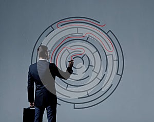 Businessman with briefcase standing over labyrinth background. B