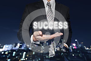 Businessman with bright SUCCESS text on hand, with defocus Bokeh night city background, business success