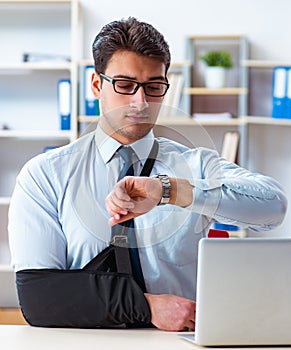 Businessman with broken arm working in office