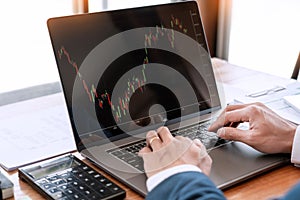 Businessman or broker looking at computer laptop analysing about stock market invest trading stocks graph analysis candle line in