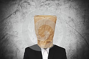 Businessman with brown paper bag on head, on dark concrete texture background