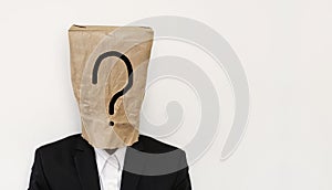 Businessman with brown paper bag on head, with question mark symbol with copy space, on white background