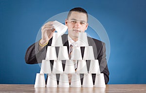 Businessman building cups' pyramid