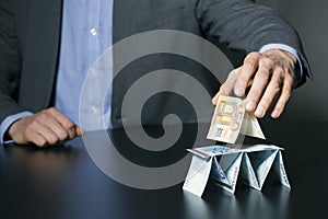 Businessman building financial pyramid from euro money