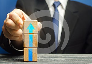 Businessman builds a tower of blocks with an up arrow. Career promotion , growth of professional skills. Business development,