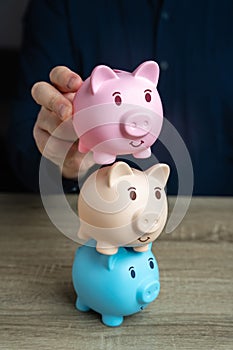 A businessman builds a tower from piggy banks. Savings and deposit banking. Multiple deposits. Healthy economy. Diversification of