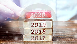 Businessman builds wooden blocks 2020. The concept of the beginning of the new year. New goals. Next decade. Trends and changes in