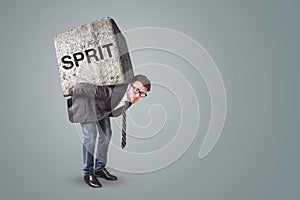 Businessman burdened by a heavy stone with the German word SPRIT on it