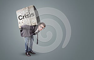 Businessman burdened by a heavy stone labeled with Crisis photo