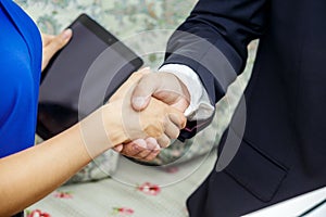 Businessman and business lady shake hands. The male in a suit and a white shirt.