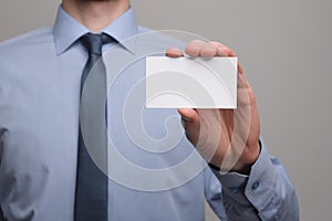 Businessman ,Business Man`s hand hold showing business card - close up shot on grey background. Show a blank piece of paper. Pape