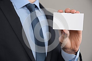 Businessman ,Business Man`s hand hold showing business card - close up shot on grey background. Show a blank piece of paper. Pape