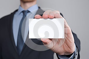 Businessman ,Business Man`s hand hold showing business card - close up shot on grey background. Show a blank piece of paper. Pape