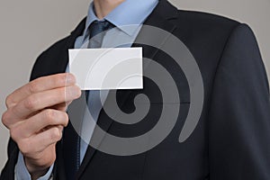 Businessman ,Business Man`s hand hold showing business card - close up shot on grey background. Show a blank piece of paper. Pape