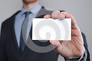 Businessman ,Business Man`s hand hold showing business card - close up shot on grey background. Show a blank piece of paper. Pape