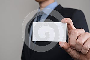 Businessman ,Business Man`s hand hold showing business card - close up shot on grey background. Show a blank piece of paper. Pape