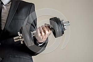 A businessman in business suit doing dumbbell biceps curl