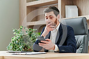 businessman in business suit laughing while looking at phone and seeing funny content or funny message