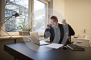 businessman businessman working on laptop in office taking notes making phone call satisfied with results on laptop in office