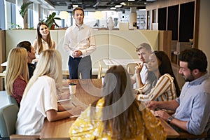 Businessman And Businesswoman Addressing Group Of Young Candidates Sitting Around Table