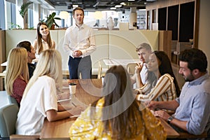 Businessman And Businesswoman Addressing Group Of Young Candidates Sitting Around Table photo