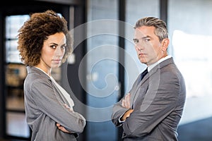 Businessman and businesswoman with arms crossed