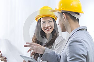 businessman and businesswoman with blueprint and helmets discuss