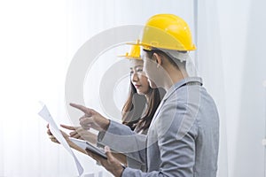 Businessman and businesswoman with blueprint and helmets discuss