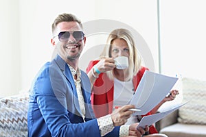 Businessman and businesswoman communicate in cafe and drink coffee and hold documents