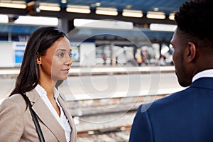 Businessman And Businesswoman Commuting To Work Talking On Railway Platform Waiting For Train