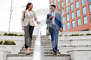 Businessman And Businesswoman Commuting To Work Walking Down Steps Outside Office Building