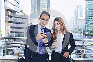 Businessman Businesswoman drinking coffee in town using smartphone outside office modern city. Hands holding take away coffee cup