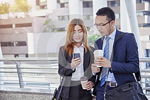 Businessman Businesswoman drinking coffee in town using smartphone outside office modern city. Hands holding take away coffee cup