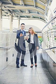 Businessman Businesswoman drinking coffee in town using smartphone outside office modern city. Hands holding take away coffee cup