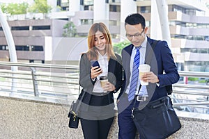 Businessman Businesswoman drinking coffee in town using smartphone outside office modern city. Hands holding take away coffee cup