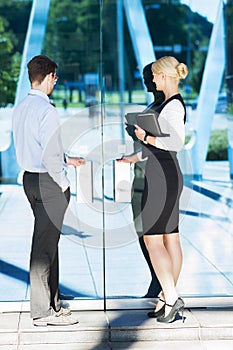 Businessman and businesswoman in formalwear being near the hotel entrance on the eve of meeting