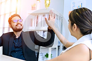 businessman and businesswoman giving hi five or touching hands and thumb up at modern office. business union and success concept