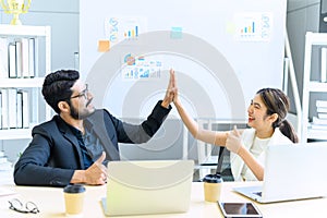 businessman and businesswoman giving hi five or touching hands and thumb up at modern office. business union and success concept