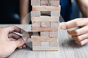 Businessman and Businesswoman hand placing or pulling wooden block