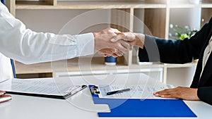 Businessman and businesswoman handshaking over the office desk after Greeting new colleague, business meetings concept