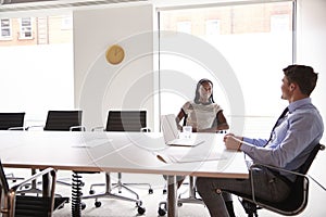 Businessman And Businesswoman Having Discussion Around Boardroom Table In Meeting Room