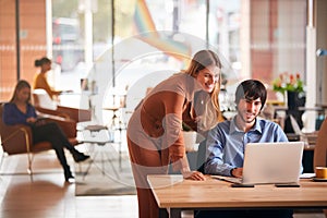 Businessman And Businesswoman Meeting By Desk In Modern Open Plan Office