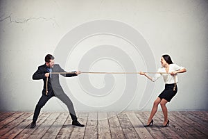 Businessman and businesswoman playing tug of war