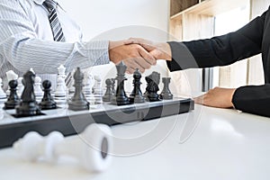 Businessman and businesswoman shaking hands after playing chess and thinking about strategy crash overthrow the opposite team and