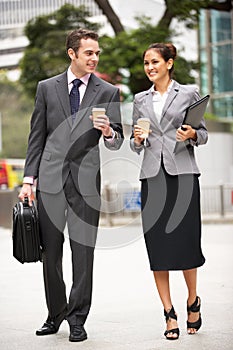 Businessman And Businesswoman Walking Along Street