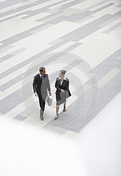 Businessman And Businesswoman Walking In Outdoor Plaza