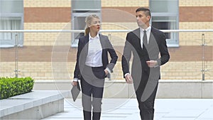 Businessman and businesswoman walking on the street of an business center, slow motion