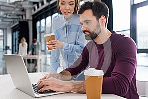 Businessman and businesswoman working with laptop in small business office