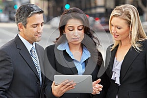 Businessman And Businesswomen Using Digital Tablet Outside